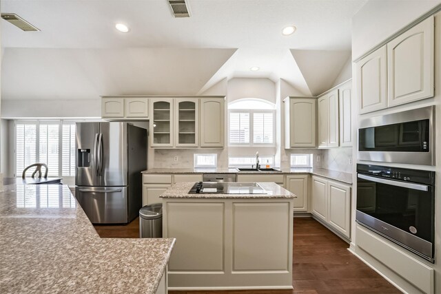 kitchen with visible vents, a kitchen island, a sink, stainless steel appliances, and vaulted ceiling