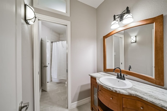 bathroom featuring a shower with shower curtain, baseboards, and vanity