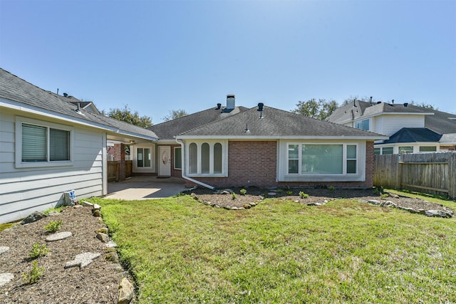 rear view of property featuring a lawn, a fenced backyard, and a patio area