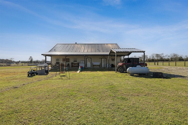 rear view of house with a standing seam roof, metal roof, a carport, and a lawn