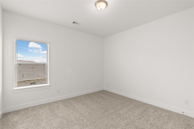 empty room with carpet flooring, visible vents, and baseboards