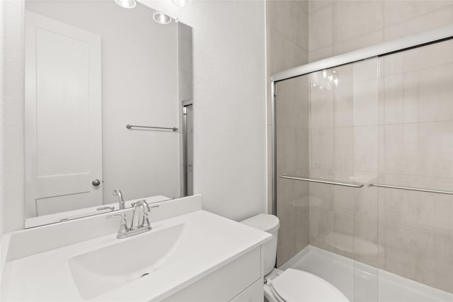 bathroom featuring a tile shower, vanity, and toilet