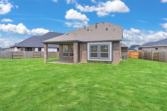 rear view of house with brick siding, a patio, central air condition unit, a lawn, and a fenced backyard