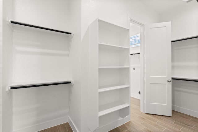 walk in closet with wood finish floors