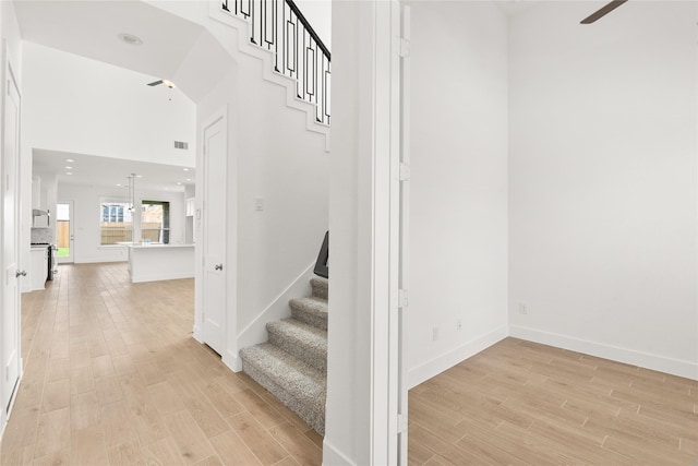 staircase featuring visible vents, ceiling fan, baseboards, and wood finished floors