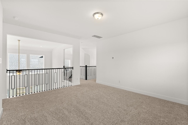 unfurnished room featuring carpet, visible vents, and baseboards