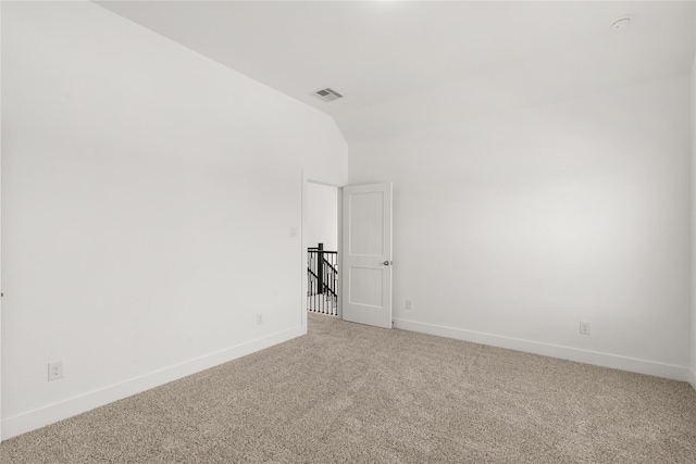 carpeted empty room with lofted ceiling, visible vents, and baseboards