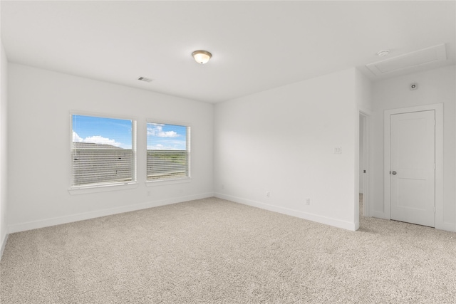 spare room with light colored carpet, visible vents, and baseboards