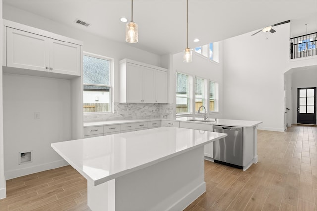 kitchen featuring light countertops, stainless steel dishwasher, a sink, and light wood-style floors