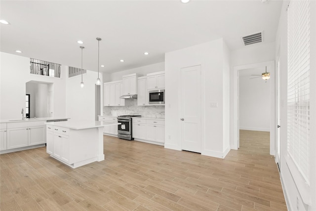 kitchen with under cabinet range hood, stainless steel appliances, a sink, visible vents, and light countertops