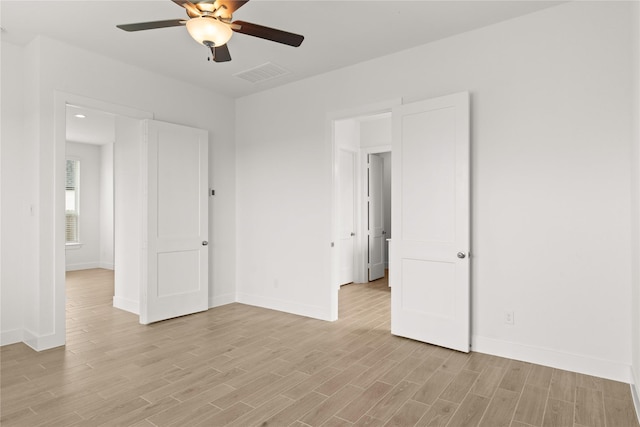 unfurnished bedroom featuring baseboards, a ceiling fan, visible vents, and light wood-style floors