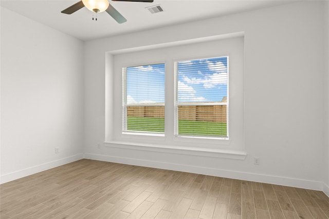 empty room featuring baseboards, a ceiling fan, visible vents, and light wood-style floors