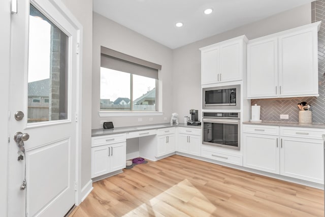 kitchen with tasteful backsplash, built in microwave, oven, light wood finished floors, and recessed lighting