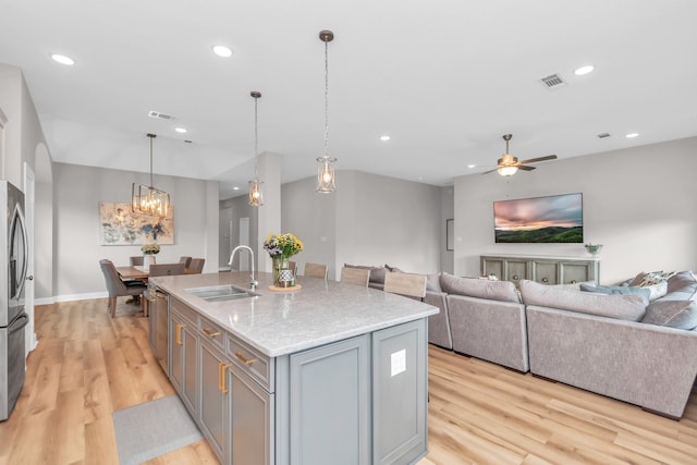 kitchen featuring stainless steel appliances, light wood-style flooring, a sink, open floor plan, and visible vents