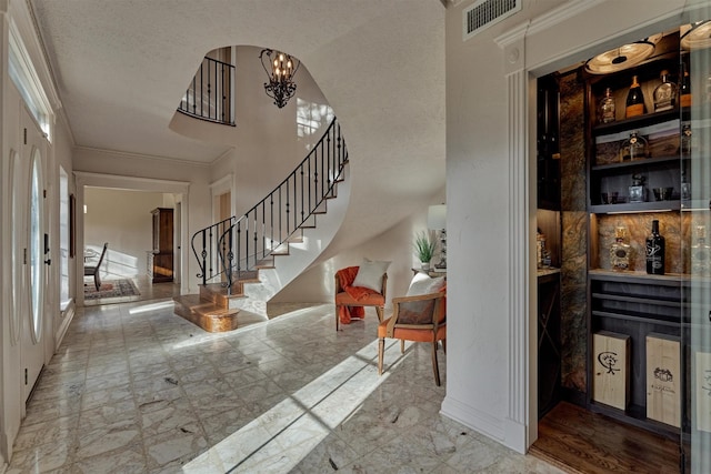 entryway with visible vents, marble finish floor, ornamental molding, stairway, and an inviting chandelier