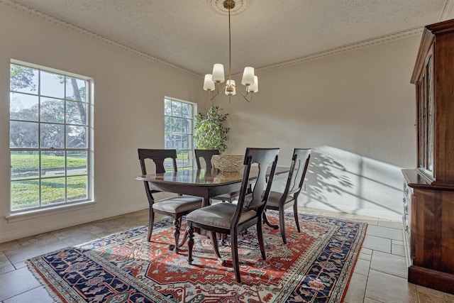 dining area with a textured ceiling, crown molding, baseboards, and a notable chandelier