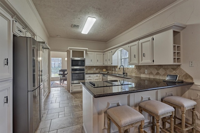 kitchen with plenty of natural light, visible vents, a peninsula, stainless steel appliances, and a sink