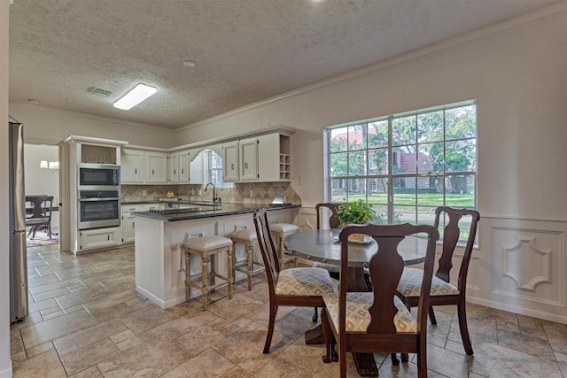 kitchen with visible vents, a peninsula, stainless steel appliances, crown molding, and a sink