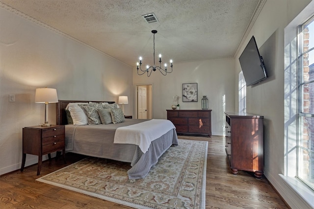 bedroom featuring a textured ceiling, multiple windows, visible vents, and wood finished floors