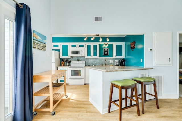 kitchen with white appliances, visible vents, and white cabinets