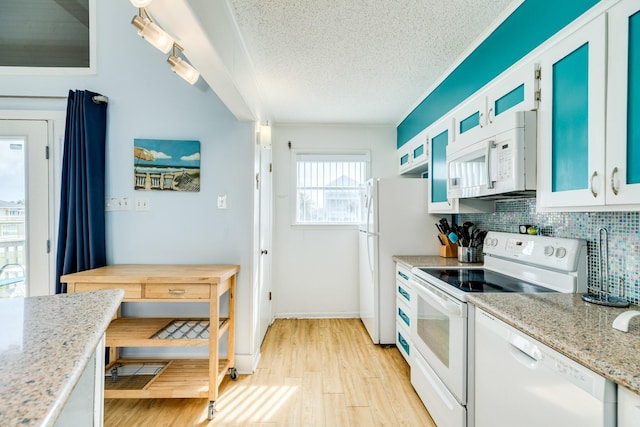 kitchen featuring white appliances, glass insert cabinets, a textured ceiling, light wood-type flooring, and backsplash