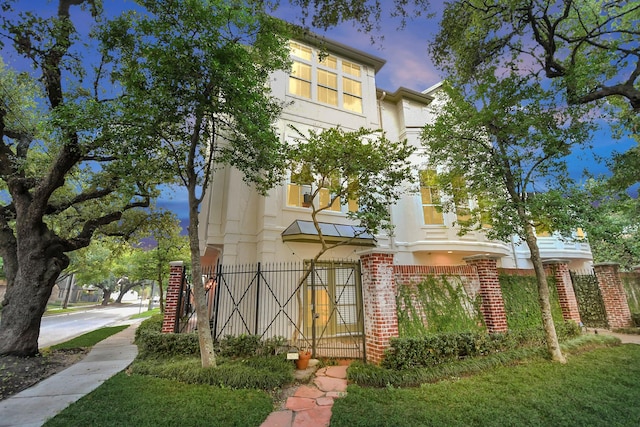 view of front facade with brick siding, fence, and stucco siding