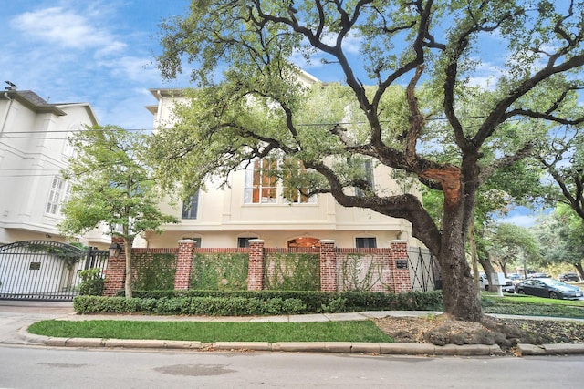 view of front of house featuring a fenced front yard, brick siding, driveway, a gate, and stucco siding