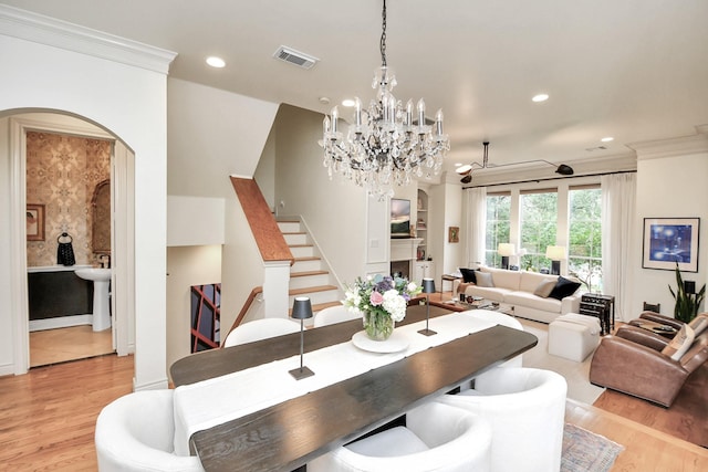 dining room with light wood-style floors, arched walkways, visible vents, and ornamental molding