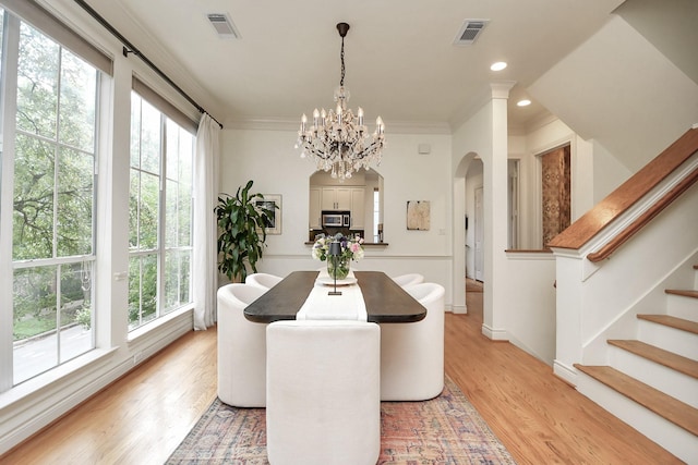 dining space with ornamental molding, stairway, light wood-type flooring, and visible vents