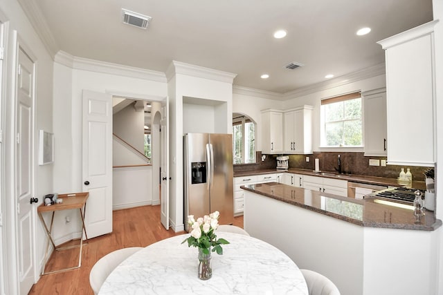 kitchen featuring arched walkways, visible vents, a sink, and stainless steel refrigerator with ice dispenser