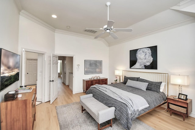 bedroom featuring lofted ceiling, visible vents, baseboards, light wood finished floors, and crown molding