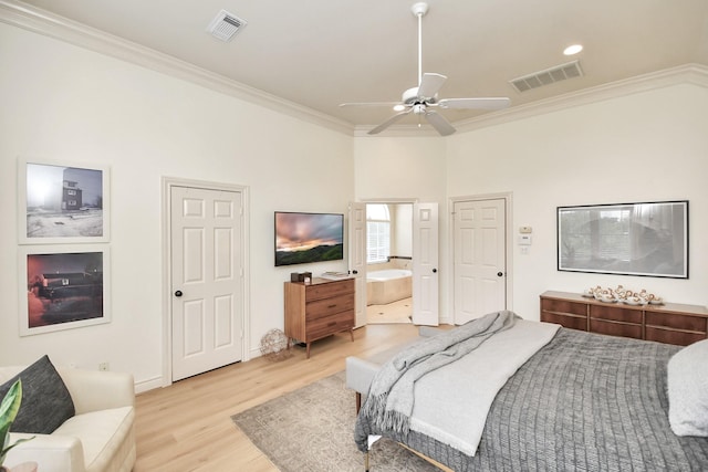 bedroom featuring light wood finished floors, ensuite bath, visible vents, and ornamental molding