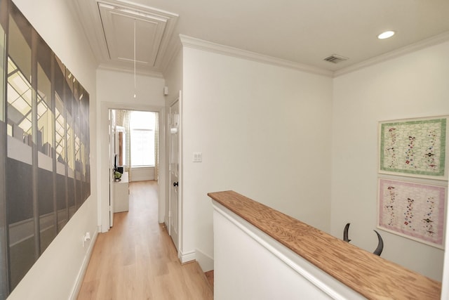 corridor with attic access, visible vents, crown molding, and light wood finished floors