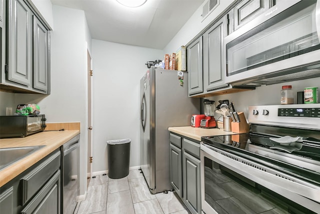 kitchen with gray cabinetry, visible vents, baseboards, light countertops, and appliances with stainless steel finishes