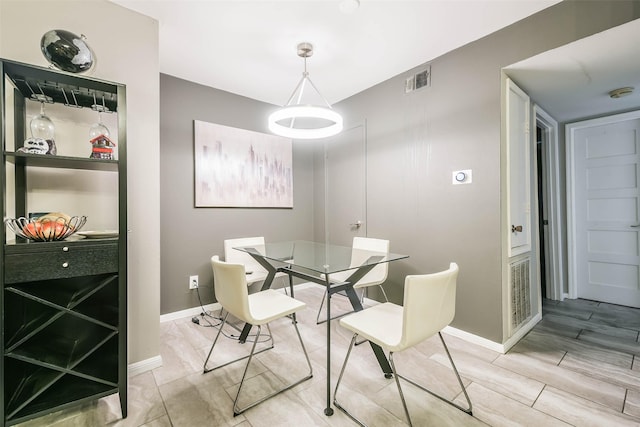 dining area with wood tiled floor, visible vents, and baseboards