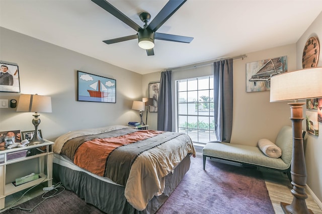 bedroom featuring dark wood-style floors, a ceiling fan, and baseboards