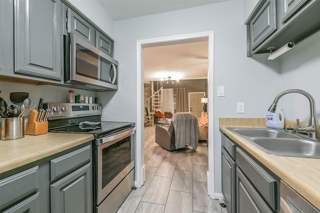 kitchen with gray cabinets, stainless steel appliances, a sink, and light countertops