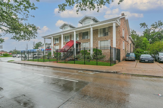 neoclassical / greek revival house with a fenced front yard and brick siding