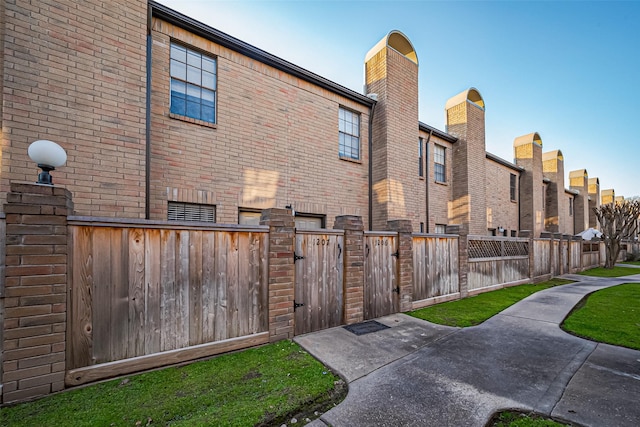 exterior space with brick siding, fence, and a gate