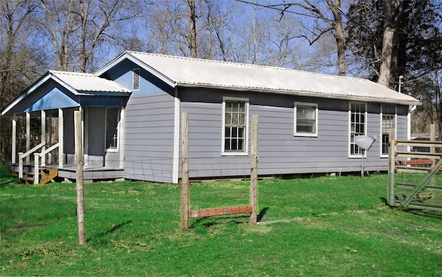 view of side of property with metal roof and a lawn