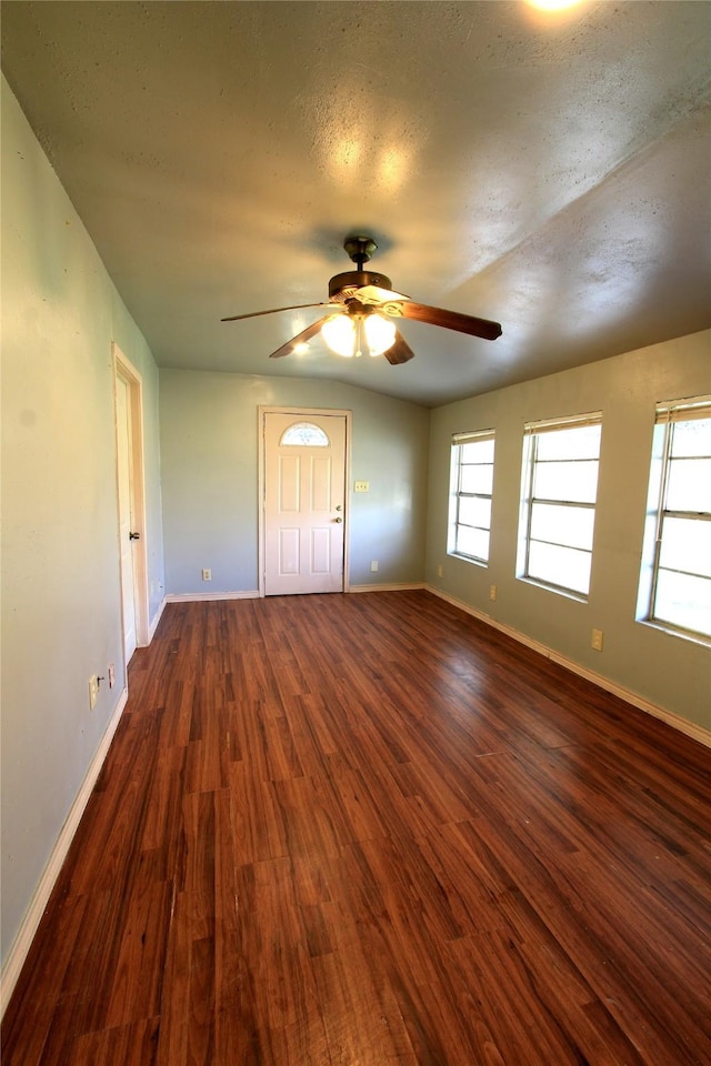 interior space featuring ceiling fan, a textured ceiling, baseboards, and dark wood-type flooring