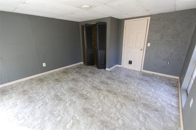 interior space with a paneled ceiling and baseboards