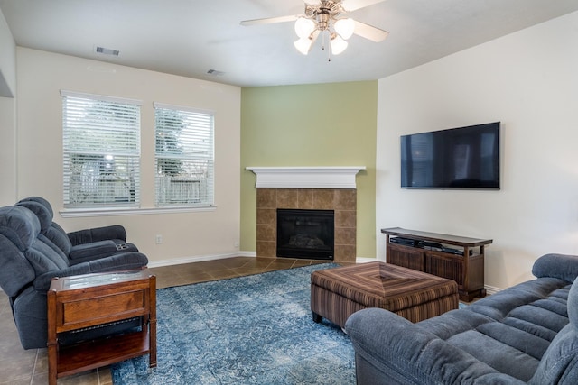 tiled living area featuring a tiled fireplace, visible vents, baseboards, and ceiling fan