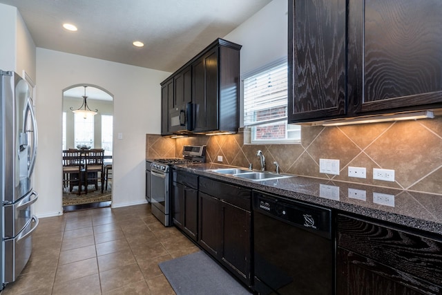 kitchen featuring tile patterned floors, decorative backsplash, arched walkways, black appliances, and a sink