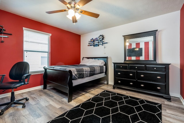 bedroom with light wood-type flooring, baseboards, and a ceiling fan