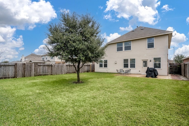 rear view of house featuring a patio, a yard, and a fenced backyard