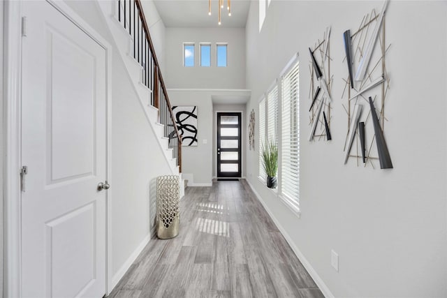 interior space featuring stairway, wood finished floors, a towering ceiling, and baseboards