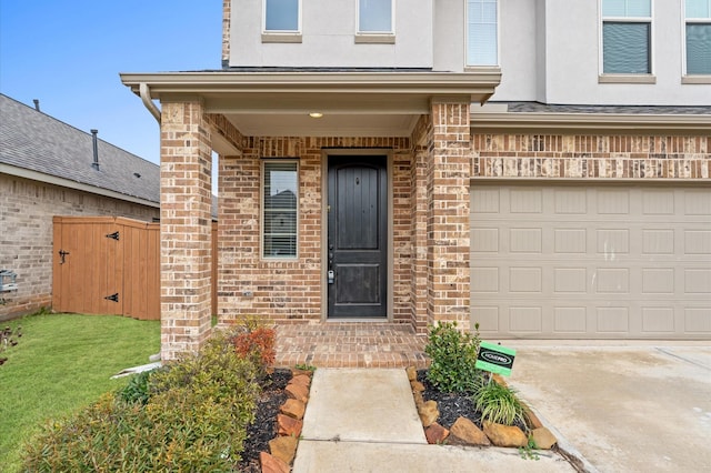 doorway to property with driveway, brick siding, a lawn, an attached garage, and stucco siding