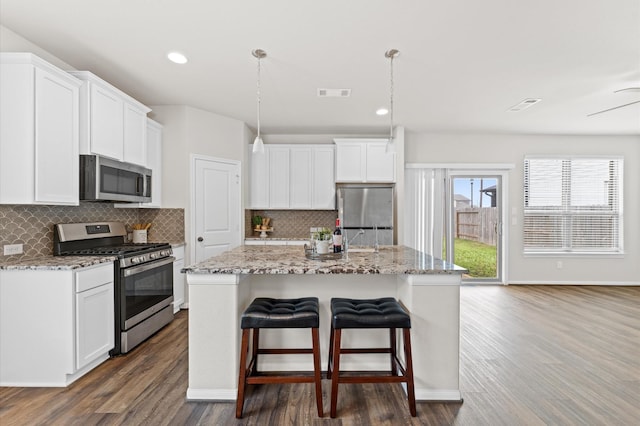 kitchen with stainless steel appliances, dark wood-type flooring, a kitchen bar, and visible vents