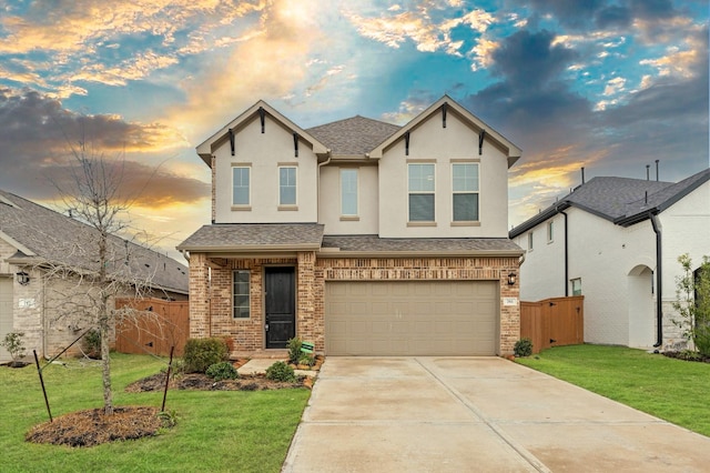 view of front of home with a garage, brick siding, a lawn, and stucco siding